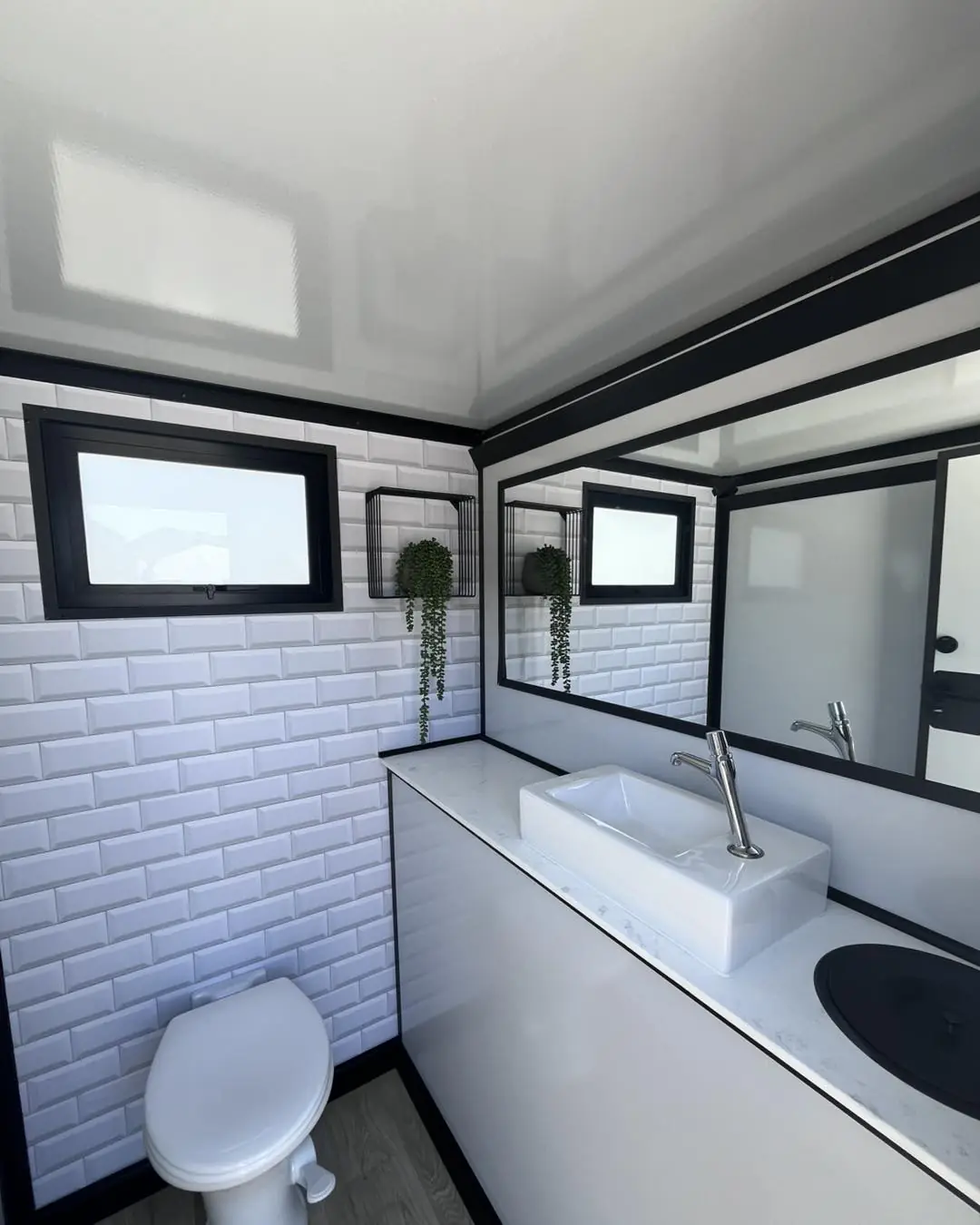 Restroom trailer interior with white tile, sink and toilet